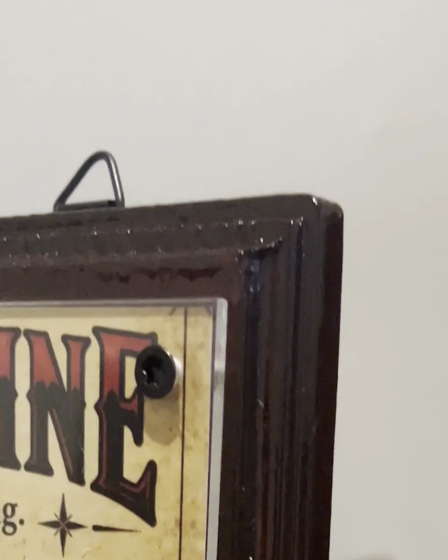 Corner of a board: the clear acrylic face held by a black screw, the hanger above